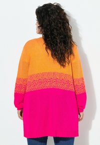 Sweter z dzianiny w pomarańczowym, żółtym i różowym gradiencie z teksturowanym wzorem. Długie rękawy, ściągacz u dołu i luźny krój. Miękka tkanina.