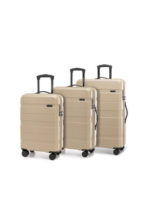 Three hard-shell suitcases in beige, featuring a ribbed design, black retractable handles, and four black wheels for mobility.