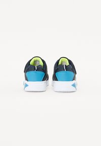 Scarpe da ginnastica navy e azzurro chiaro con una parte superiore texturizzata, suola bianca e accenti verde neon all'interno e sul tallone.
