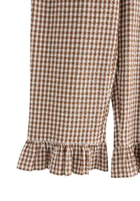 Brunt og hvidt gingham-stof med flæsekanter, del af et beklædningsstykke, vist mod en hvid baggrund.