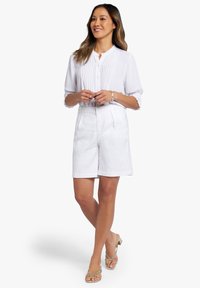 Witte blouse met plooien, knoopsluiting en gek gathered mouwen, gecombineerd met witte shorts met zijzakken en een relaxed fit.