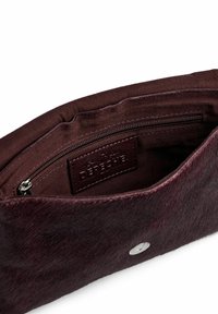 Borsa bordeaux realizzata in materiale testurizzato, con tasca con zip e etichetta in pelle con marchio all'interno. Dettaglio circolare in metallo argentato visibile.