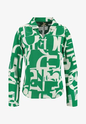 Blouse verte à manches longues avec des formes géométriques abstraites blanches et un col avec une petite ouverture au niveau de l'encolure.
