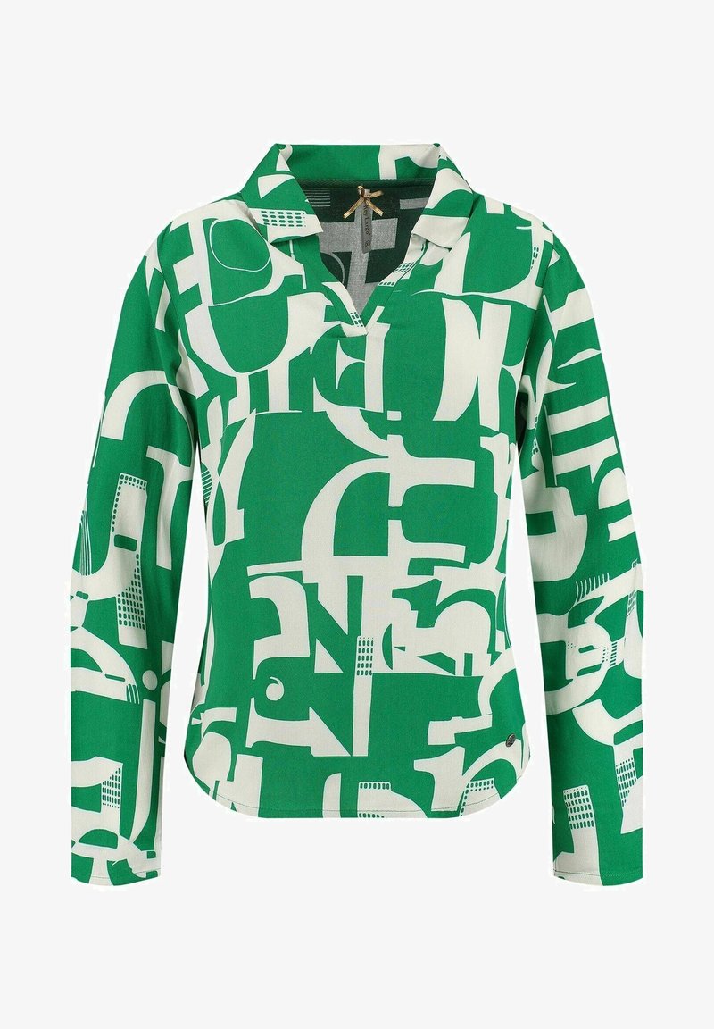 Blouse verte à manches longues avec des formes géométriques abstraites blanches et un col avec une petite ouverture au niveau de l'encolure.