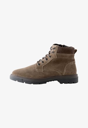 Brauner Wildleder-Schnürstiefel mit gepolstertem Kragen und schwarzer robuster Gummisohle, von der Innenseite gezeigt.
