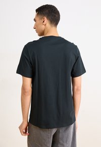 Camiseta negra de manga corta con cuello redondo, fabricada en algodón, con corte recto y una textura suave.