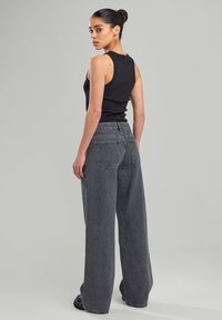Black tank top paired with gray pinstriped wide-leg pants. The pants feature a high waist, elastic waistband, and back pockets.