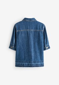 Vue de dos d'une veste en denim bleu moyen avec manches longues et poignets à boutons sur un fond blanc.