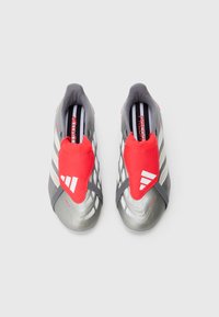 Grå fotballsko med en rød elastisk tunge og hvite striper. Har en teksturert overflate for grep og en strømlinjeformet form.