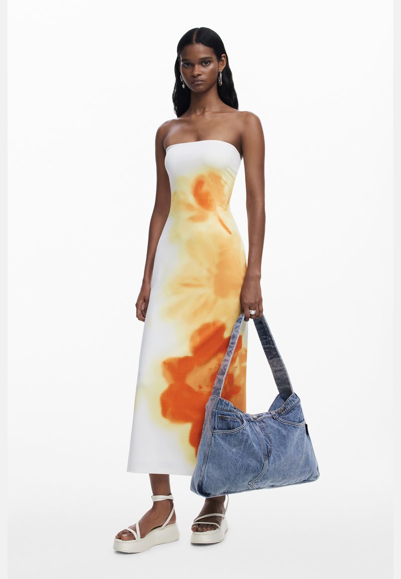 Trägerloses Maxikleid mit einem Farbverlaufdesign in Weiß und Orange, kombiniert mit einer Jeans-Schultertasche und klobigen weißen Sandalen.