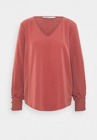 Rostfarbige Bluse mit V-Ausschnitt, langen Ärmeln, die an den Manschetten gerafft und mit Knopfakzenten versehen sind, aus glattem, leichtem Stoff gefertigt.