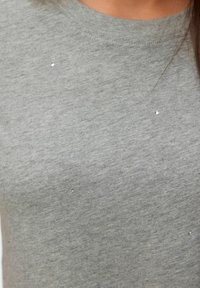 T-shirt in cotone grigio con collo a giro e piccole paillettes riflettenti sparse sul davanti per un tocco di dettaglio in più.