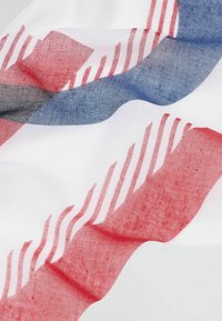 Lekki, przezroczysty szalik w czerwono-biało-niebieskie wzory geometryczne z subtelnym teksturowanym wzorem, z falującymi liniami i przezroczystością.