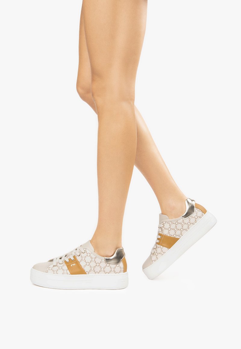 Sneaker color sabbia chiaro con soletta bianca, caratterizzate da una tomaia a motivo, dettagli dorati e un tacco metallico. I lacci sono bianchi e piatti.