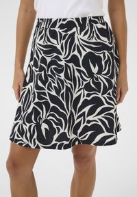 Jupe à motif floral noir et blanc, fabriquée en tissu texturé, dotée d'une taille élastique et d'un design évasé.