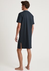 Donkerblauwe, knielange unisex t-shirt met korte mouwen, zijinsneden en een ronde halslijn, gemaakt van een gladde katoenen mix.