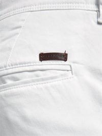 Witte stofbroek met een gestructureerd oppervlak, voorzien van een klein bruin leren label op de achterzak.