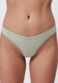 Lichtgroene geribbelde stofstring met golvende kantranden, met een klassieke snit en een gladde textuur. Ontworpen voor comfort en pasvorm.