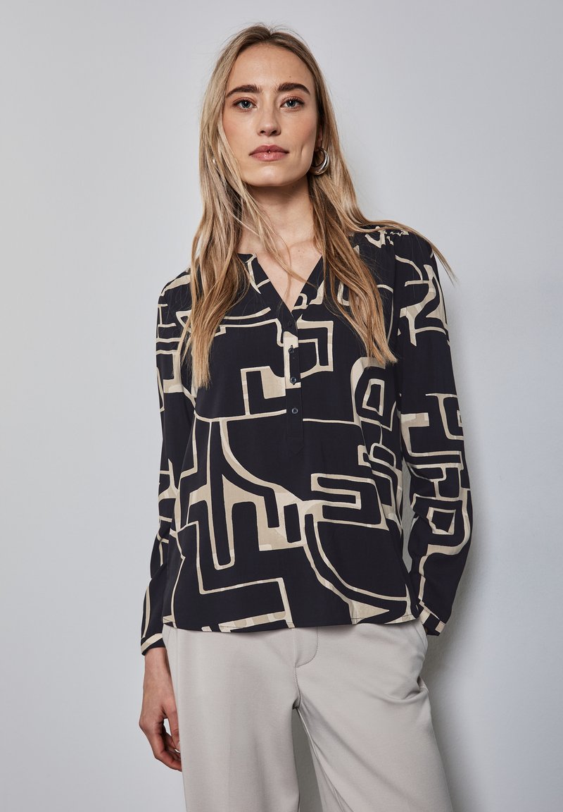 Langärmliges, knöpfbares Hemd in Schwarz und Beige mit abstrakten geometrischen Mustern. Leichter Stoff mit V-Ausschnitt und lockerer Passform.