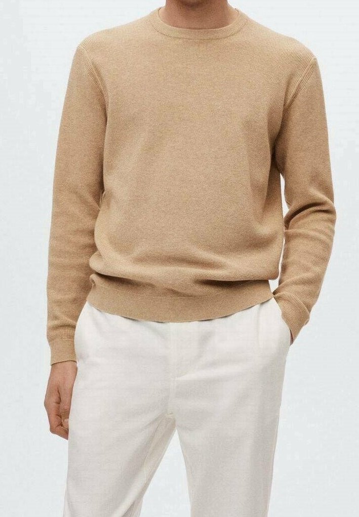 Beige gebreide trui met geribbelde textuur, ronde hals en lange mouwen, gecombineerd met lichtgekleurde broek. Eenvoudig, minimalistisch ontwerp.