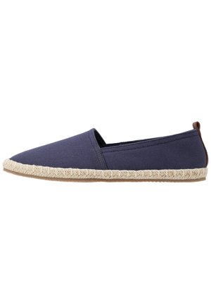 Espadrille en toile navy avec une semelle en jute et un accent marron au talon. Présente un design à enfiler et un bout pointu.