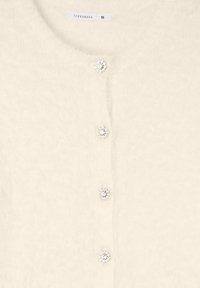 Cardigan crema realizzato in materiale morbido e peloso. Presenta bottoni simili a gioielli, scollatura rotonda e maniche a lunghezza completa. Etichetta di taglia S visibile.