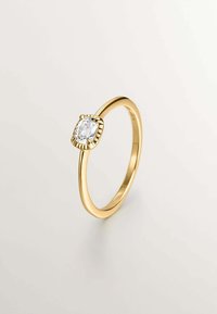 Anillo de oro con una piedra clara ovalada asegurada por un engaste texturizado. La banda es lisa, con un acabado pulido.