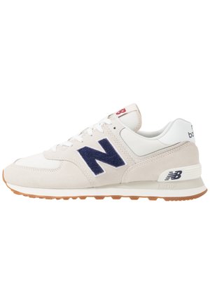 Zapatilla blanca y beige con logotipo "N" azul marino, diseño con cordones, suela acolchada y suela exterior color goma.
