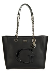Sac cabas GUESS en cuir noir avec un grand "G" brillant à l'avant, des anses en chaîne dorée et des étiquettes métalliques rondes de la marque suspendues à une sangle.