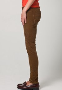 Bruine corduroy jeans met een nauwsluitend ontwerp, een gladde textuur en een subtiele glans. Voorzien van een zijzak en een klassieke vijfzakkenstijl.