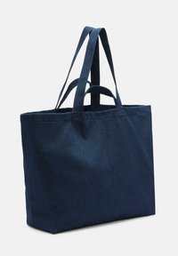 Navyblaue Tragetasche aus Canvas mit langen, robusten Griffen, die eine einfache rechteckige Form hat und keine sichtbaren Verzierungen aufweist.