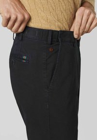 Chino navy en coton, présentant une coupe slim, des poches avant et une fermeture à bouton avec un détail rayé multicolore sur la poche arrière.