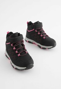 Scarpe da trekking nere con accenti rosa, dotate di materiale sintetico testurizzato, cinturino in velcro regolabile e suole in gomma robuste con motivi di grip.