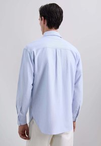 Camicia a maniche lunghe blu chiaro realizzata in tessuto a righe, con colletto classico, pieghe posteriori e polsini con bottone; orlo leggermente curvo.