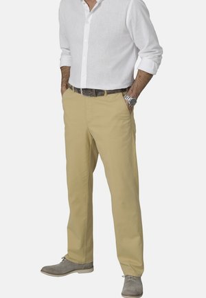 Beige chinos made of cotton, featuring a straight-leg design. Worn with a white button-up shirt and grey shoes. Brown belt visible.