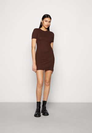 Vestido castanho, justo, de mangas curtas, feito de tecido texturizado, que chega até à metade da coxa, combinado com botas ankle pretas. Decote redondo simples.