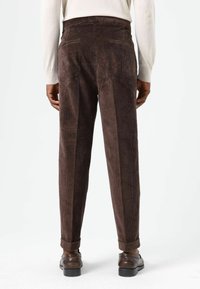 Pantalon en velours côtelé marron avec une finition texturée, présentant une coupe droite, deux poches arrière et des revers retournés.