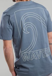 Gray cotton t-shirt featuring a large white wave graphic and the word "WAVES" printed below. Short sleeves and a relaxed fit.