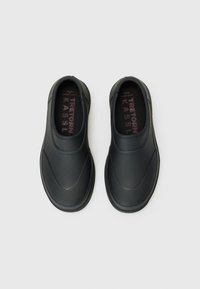 Black slip-on shoes with a smooth, waterproof upper and round toe. Textured sole and inside features branded in pink letters.