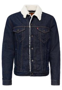 Mörk denimjacka med en mjuk vit faux fuskpälskrage, som har två bröstfickor, metallknappar och gula sömnadsdetaljer.