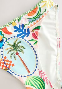 Kolorowa tkanina z tropikalnymi wzorami owoców i palm, zawierająca różowe, zielone, niebieskie, pomarańczowe i żółte motywy na białym tle.