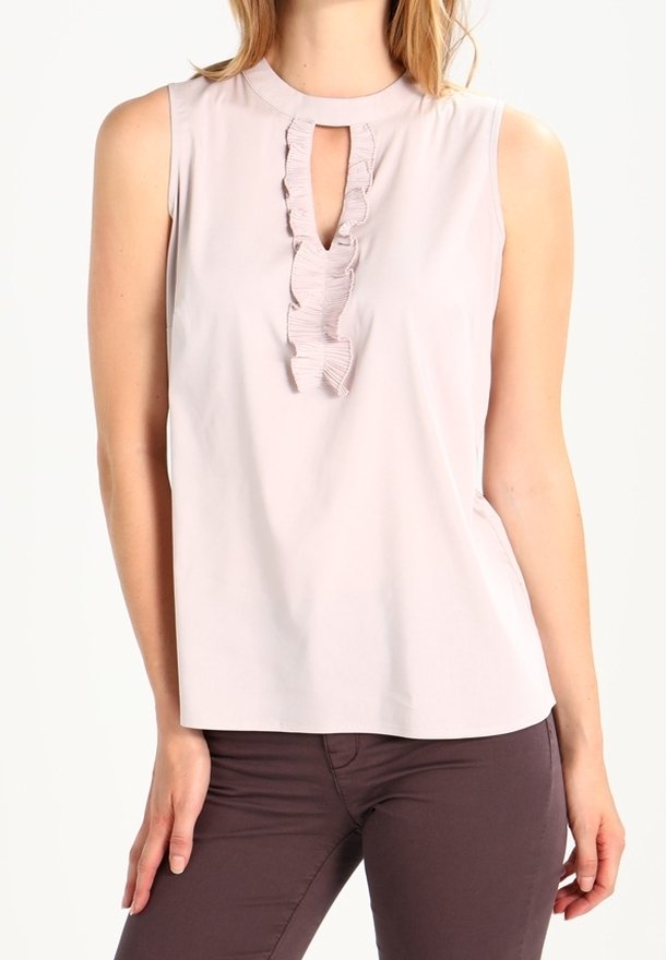 Blusa senza maniche rosa chiaro con colletto alto, caratterizzata da un'apertura a chiave e dettagli con volant lungo la parte anteriore. Texture liscia.