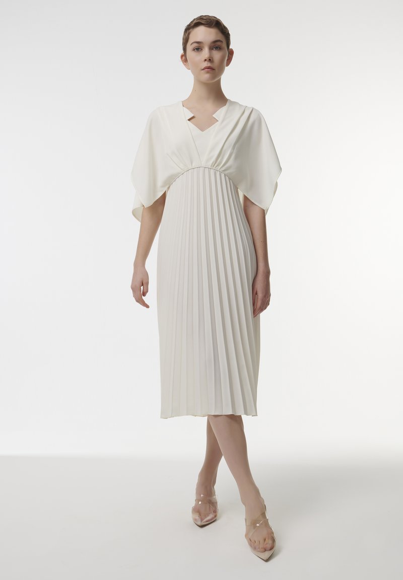 Plissé midi-jurk in off-white stof, met een diepe V-hals, brede mouwen en een getailleerde taille. Gladde, vloeiende textuur over de gehele jurk.