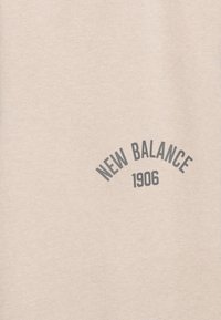 Beige bavlněná mikina s zakriveným šedým potiskem "NEW BALANCE 1906" uprostřed. Hladká textura a ležérní design.