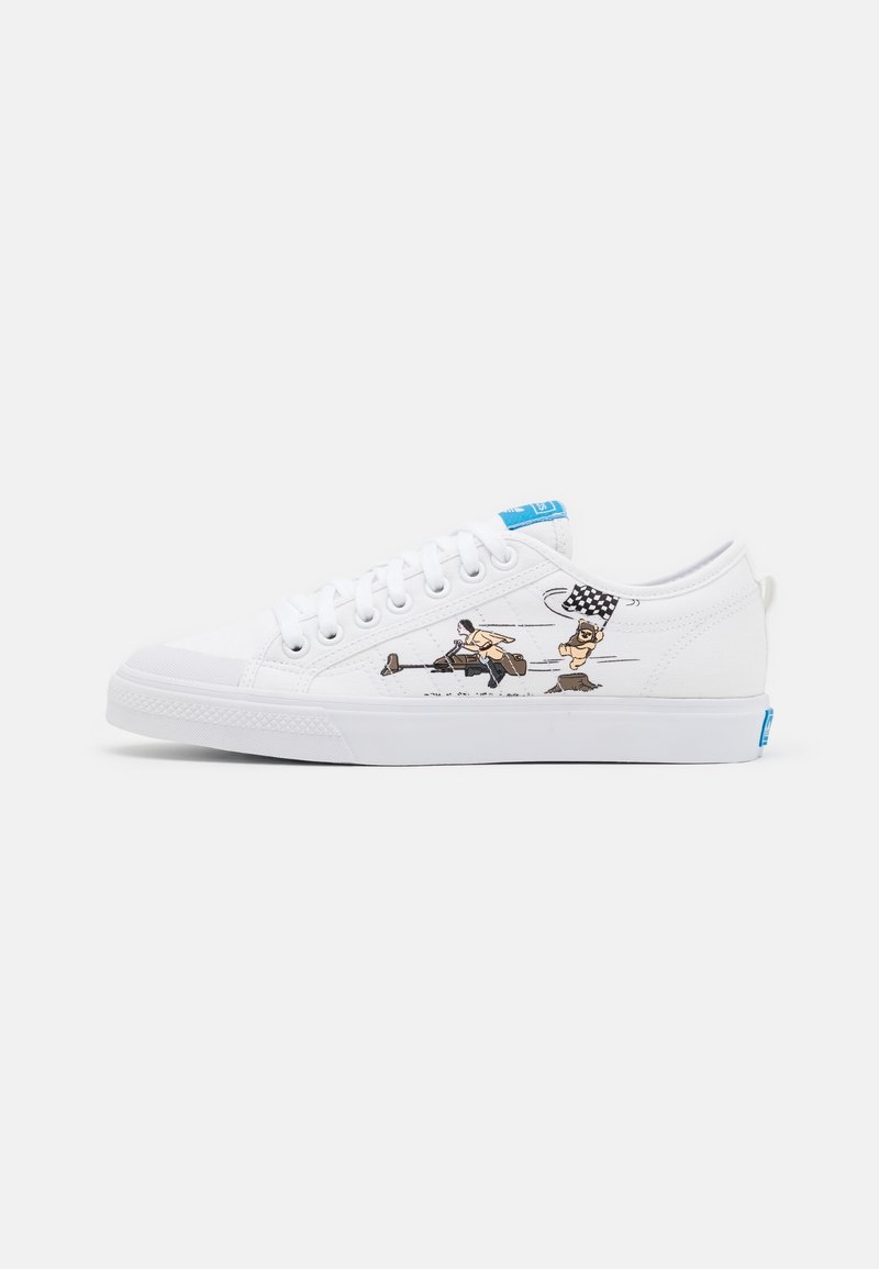 White canvas sneakers with round toe, blue accent on the tongue, and side graphic featuring a character and a checkered flag design.