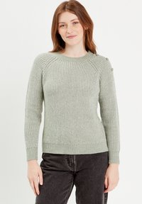 Pull en tricot vert clair avec texture côtelée, encolure ronde et manches longues. Présente des accents de boutons sur l'épaule et une taille ajustée.