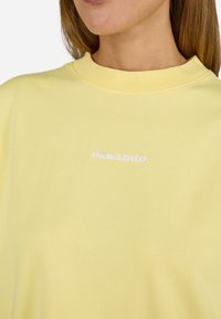 Gul bomull t-skjorte med rund hals. Har hvit "PEGADOR" tekstlogo på brystet. Myk tekstur, uformell design.