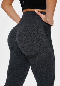 Black high-waisted leggings with a textured finish, featuring a contoured back. The design includes a subtle logo and seamless construction.