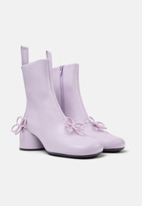 Stivaletti alla caviglia in pelle lilla con cerniera frontale, tacco a blocco e dettagli decorativi a forma di anello sui lati. Texture liscia e design moderno.