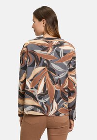 Floral patterned long-sleeve top featuring shades of brown, gray, and cream. Made from textured fabric with a relaxed fit and rounded neckline.
